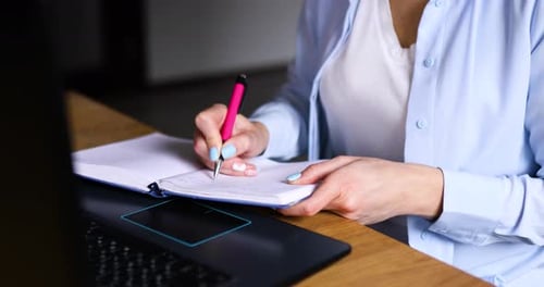 Female Making Notes in Planner While Working on Remote Project in Home Office