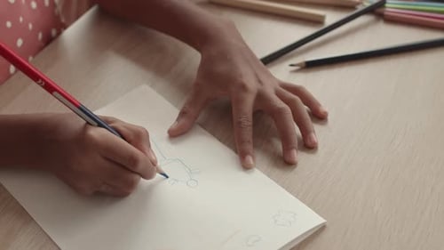 Child Drawing with Blue Colored Pencil on Paper
