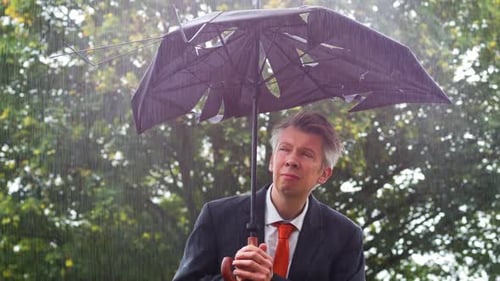 Man Holds Broken Umbrella in the Rain