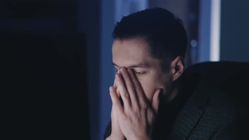 Tired Young Businessman Man Works at a Laptop Computer Late at Night Suffers From Fatigue
