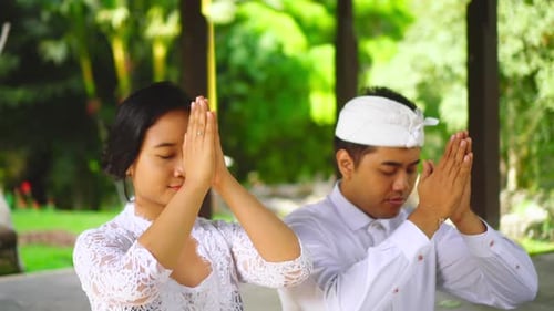 Praying with putting hands to forehead. Young family in Bali pray in temple. Culture, people