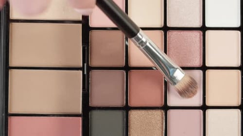 Makeup Brush Applying Product on Beauty Palette