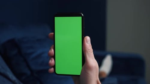Close Up Shot of Guy Lying on Couch at Night, Holding a Smartphone with Chroma Key Mock Up Green