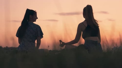 Women Meditating in Field During Sunset