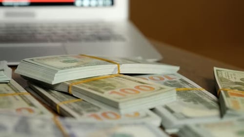 Stacks of Money Next to a Laptop