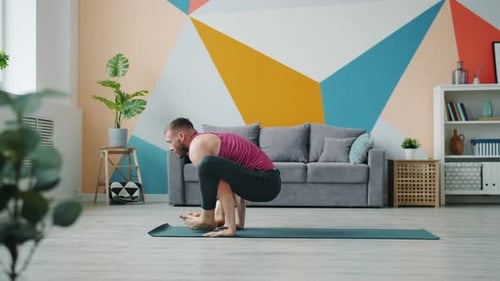 Male Yoga Student Exercising at Home Doing Arms Balancing Asana on Rubber Mat