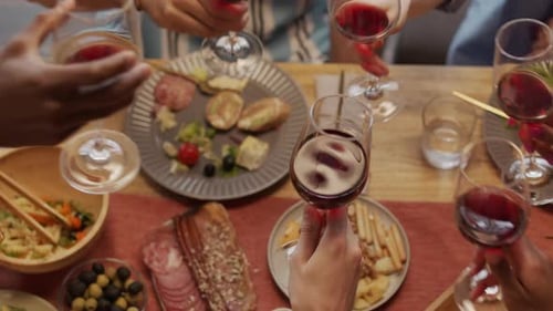 Friends Toasting with Wine Over Delicious Food Spread
