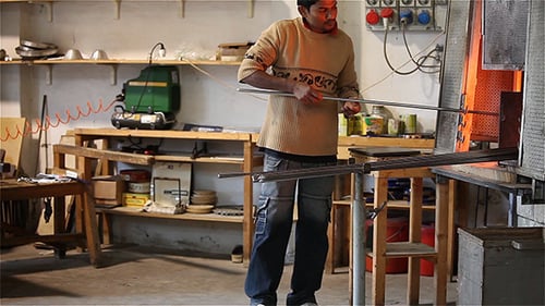 Glass Blower Shaping Glowing Glass in Workshop