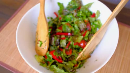 Fresh Salad Tossed with Wooden Spoons in Bowl