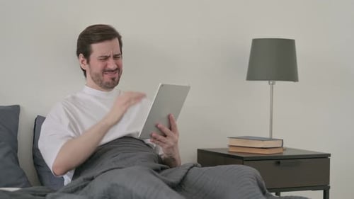 Man in Bed Upset with Tablet Content