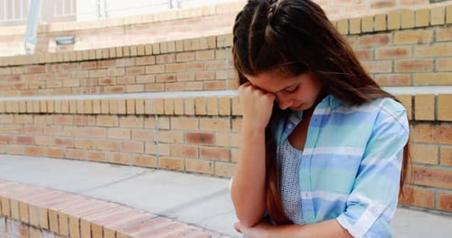 Depressed girl sitting on stairs in campus