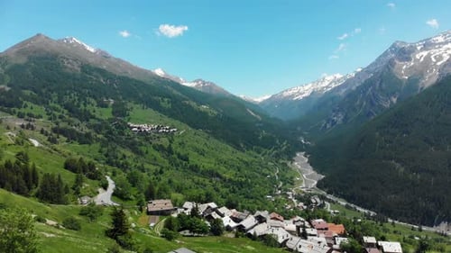 Luftbild: Flug über Alpental, malerische, waldbedeckte Bergkette und kurvenreiche Straße