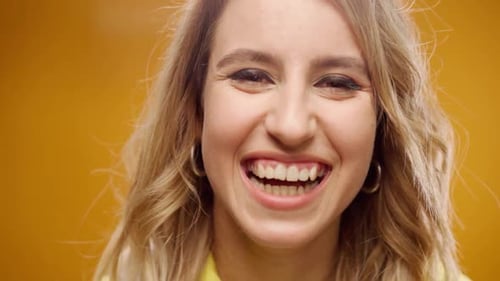 Young Woman Listening to Music with Headphones Against Yellow Background