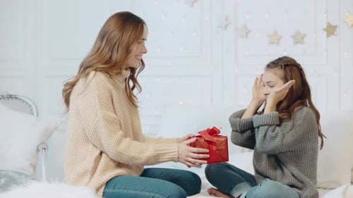 Mother Gives Present to Daughter on Bed