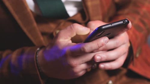 Man Holding Smartphone and Typing on the Screen