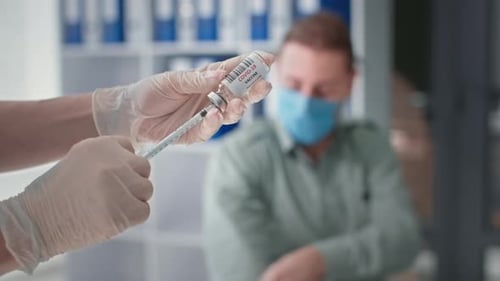 Young Man Wearing Medical Mask on His Face is Vaccinated with Covid Vaccine to Protect Against