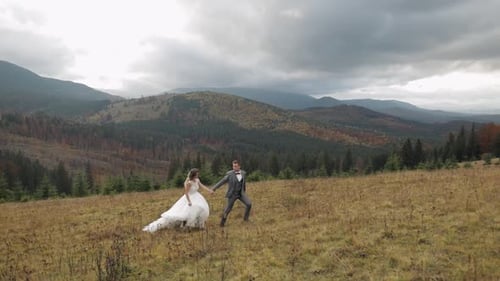 Lovely Young Newlyweds Bride Groom Running on Mountain Slope Holding Hands Wedding Couple Family
