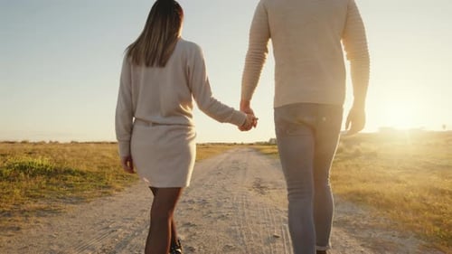 Junge und Mädchen gehen an der Hand auf der unbefestigten Straße