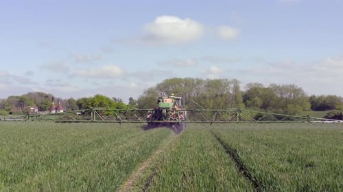 Tractor Spraying a Green Field on a Farm
