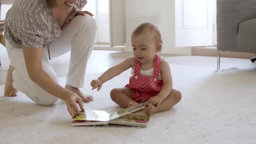 Mother Reading Picture Book with Adorable Infant on Rug