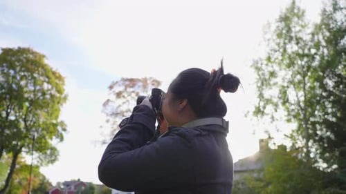 Woman Taking Photos with Camera in City Park