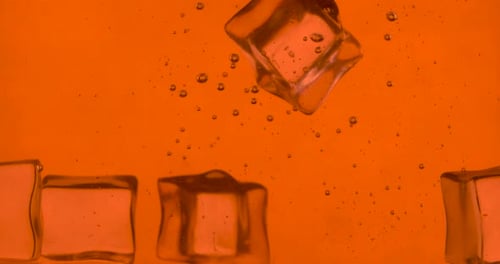 Ice Cubes Dropped into Orange Liquid