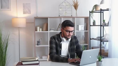 Young Adult Typing on Laptop at Home Desk