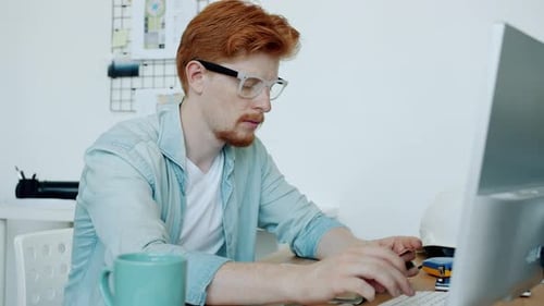 Zeitlupe eines nachdenklichen Architekten beim Tippen auf dem Laptop in Innenräumen in einem modernen Büro