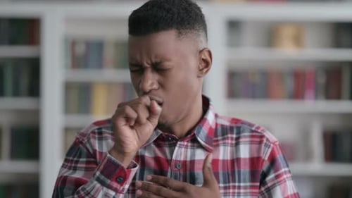 Adult Coughing in Front of Bookshelf