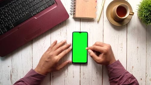 Businessman Using Smart Phone with Green Screen on Office Desk