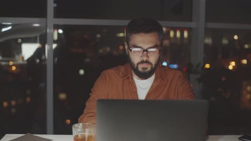 Businessman Working on Laptop in Dark Office in Evening