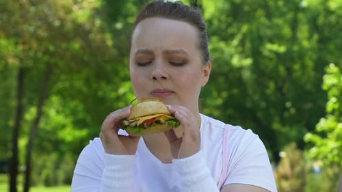 Woman Eats Burger in a Green Park