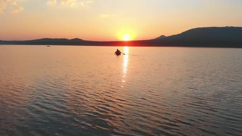 Lonely Man Sailing in a Boat on River with Paddles on Sunset