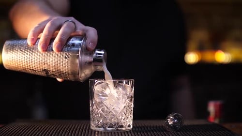 Bartender Pouring Cocktail in Glass with Ice