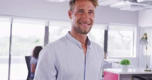 Professional businessman smiling while standing in modern office in slow motion