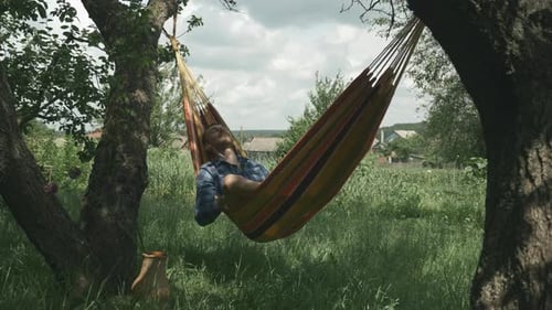 Man enjoying vacation and swinging in hammock. Relax in hammock. Camping. Male lying in hammock