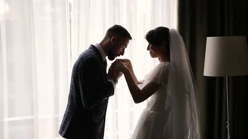 Romantic Bride and Groom Holding Hands by Window