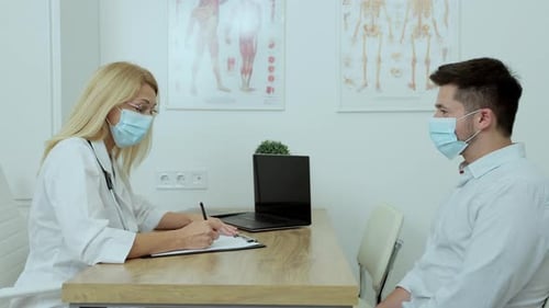 In Doctor Office Man Patient in Medical Mask Talks to His Female Doctor
