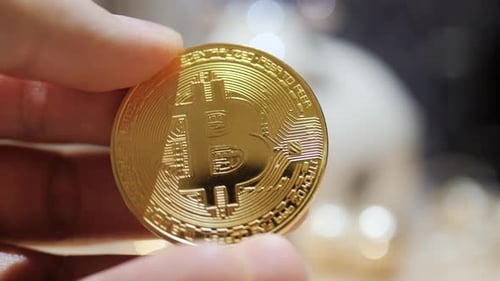 Shiny Gold Bitcoin Held in Hand Close Up