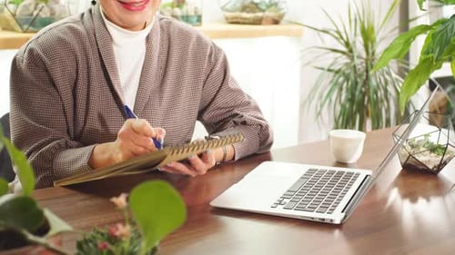 Serious Senior Business Woman Writing Work Issues in Notebook