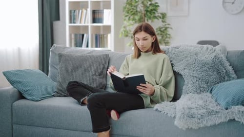 Woman Reading Book on Couch in Living Room