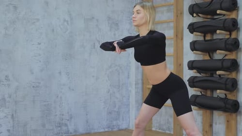 Young fit sporty girl in black top, black leggings does exercises on mat in gym. Doing sports