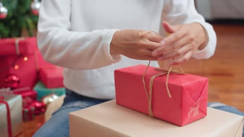 Person Tying Christmas Gift with Twine at Home