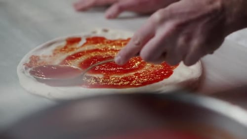 Étaler la sauce tomate sur la pâte à pizza