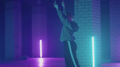 A Steel Woman Dances Hiphop Freestyle in a Modern Style in a Hall with Neon Light in Purple Blue