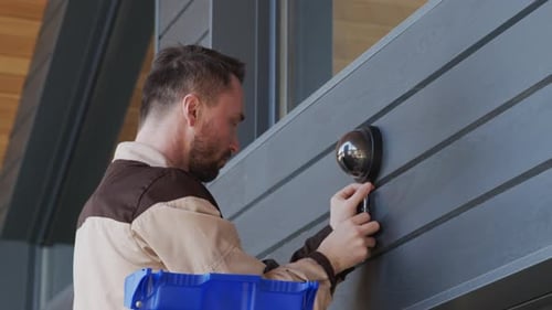 Man Installing Security Camera on Modern House