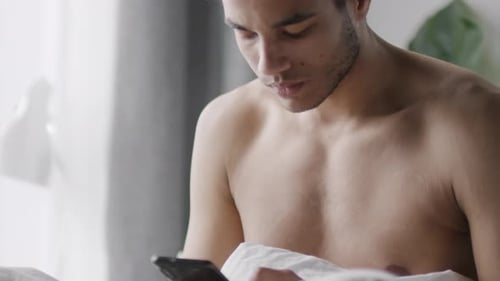 Young Adult Uses Mobile Phone in Bed