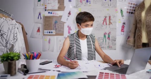 Fashion designer woman wear mask draws a sketch of women's clothing