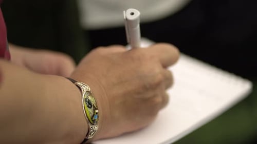 Close-up view of hand of man writing in notebook