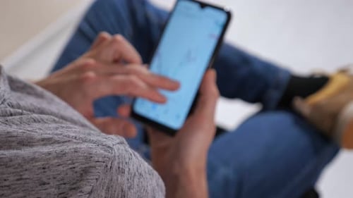 Unrecognizable Man with Phone Examines Stock Market Charts Analysis